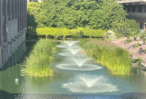 Working fountain water pumps at the Barbican Estate, surrounded by lush greenery.